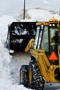 Yellow snow removal equipment moves a large pile of snow.