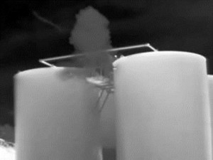 grainy black and white photo of two large tanks, with a plume of gray above