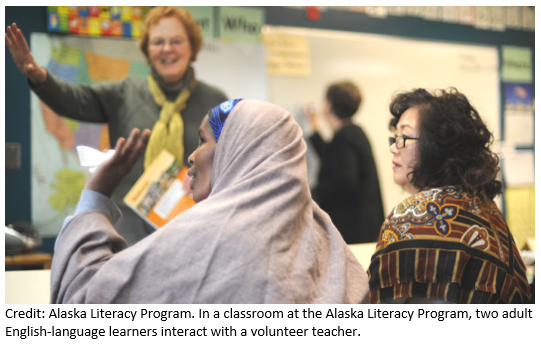 Dos adultos que est&aacute;n aprendiendo ingl&eacute;s interact&uacute;an con un profesor voluntario en un aula del Programa de Alfabetizaci&oacute;n de Alaska.