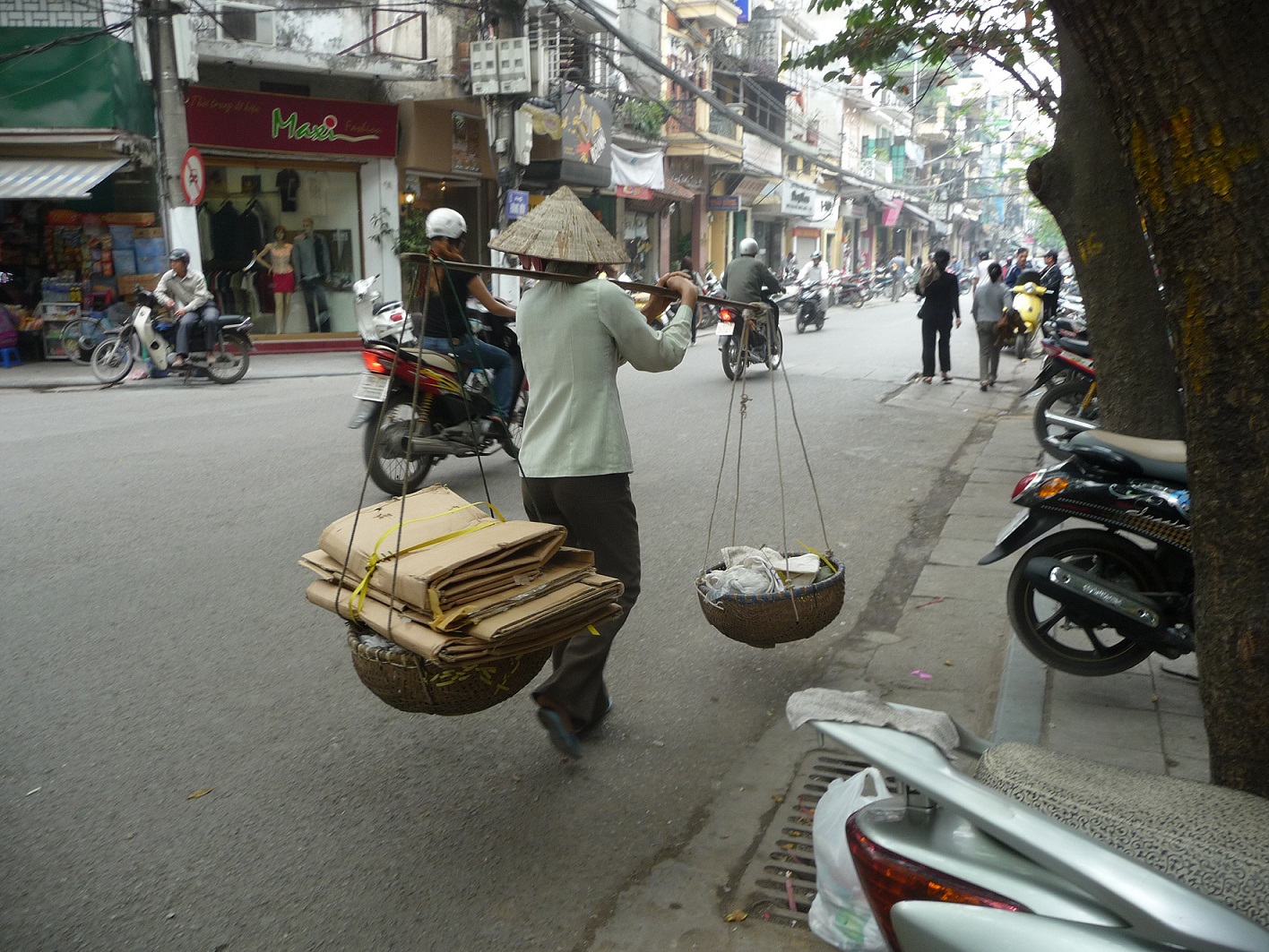 Person walking int he street carrying materials in baskets.