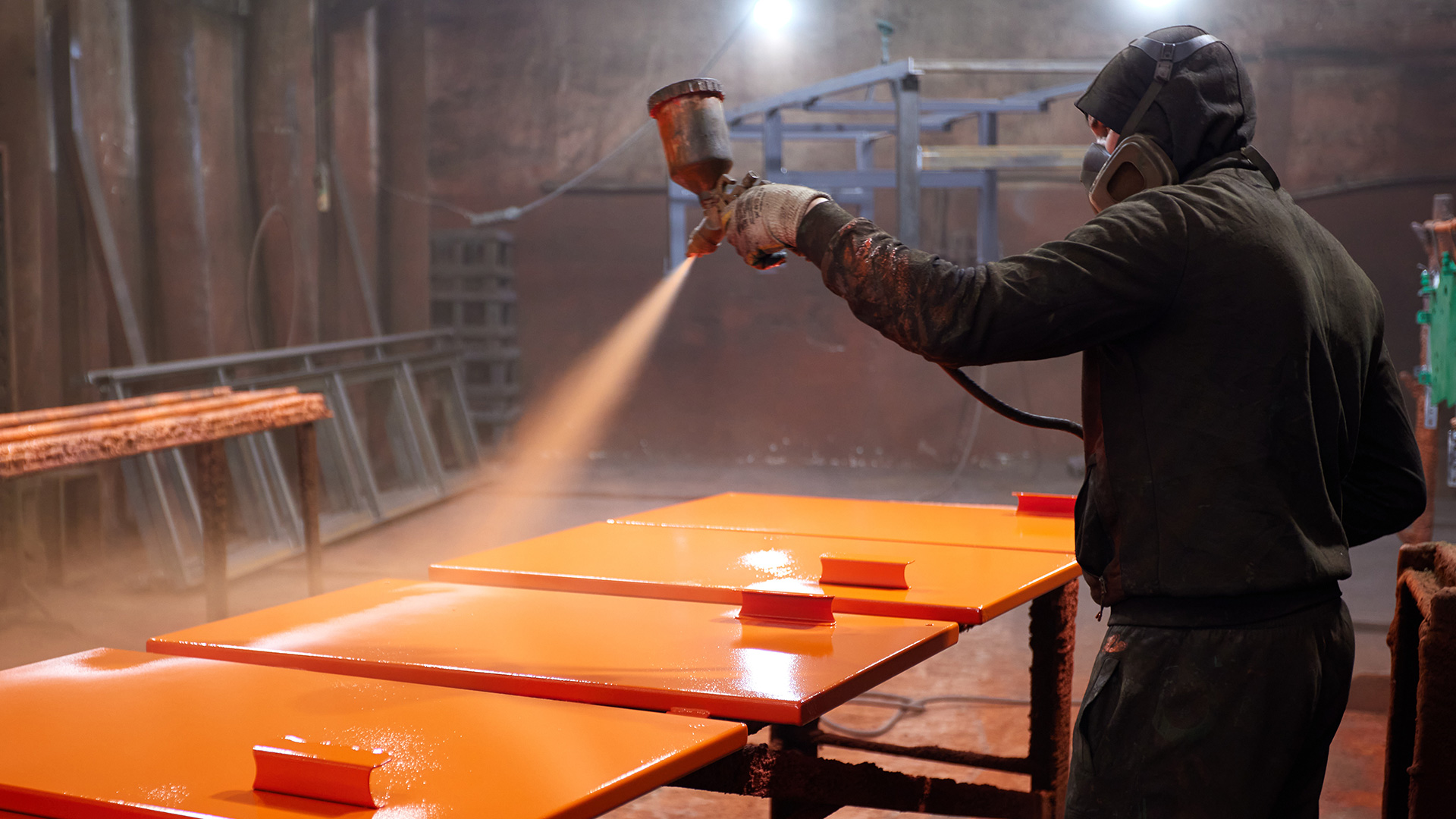 Worker spray painting a car part.