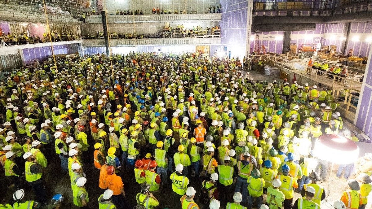 Large group of construction workers gather at worksite to listen to fall prevention presentation