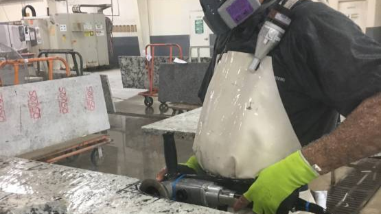 Worker grinding stone countertop using wet method.