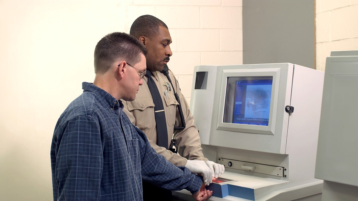 Correctional officer taking fingerprints of a detained person.