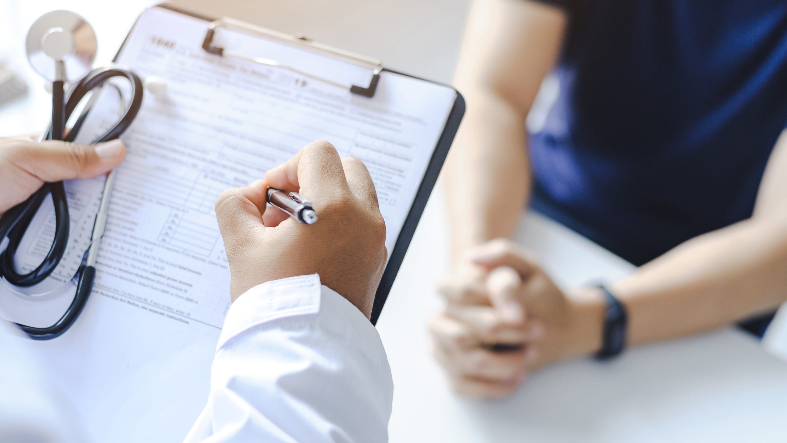 Doctor giving prescription to the patient and filling up medical form at a clipboard Doctor giving prescription to the patient and filling up medical form at a clipboard.