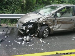 --no title-- A car damaged from an accident on the side of the road with broken glass, a smashed driver side door and fender