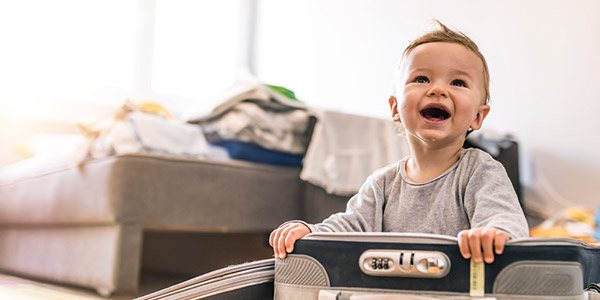 A smiling child sitting in a suitcase.
