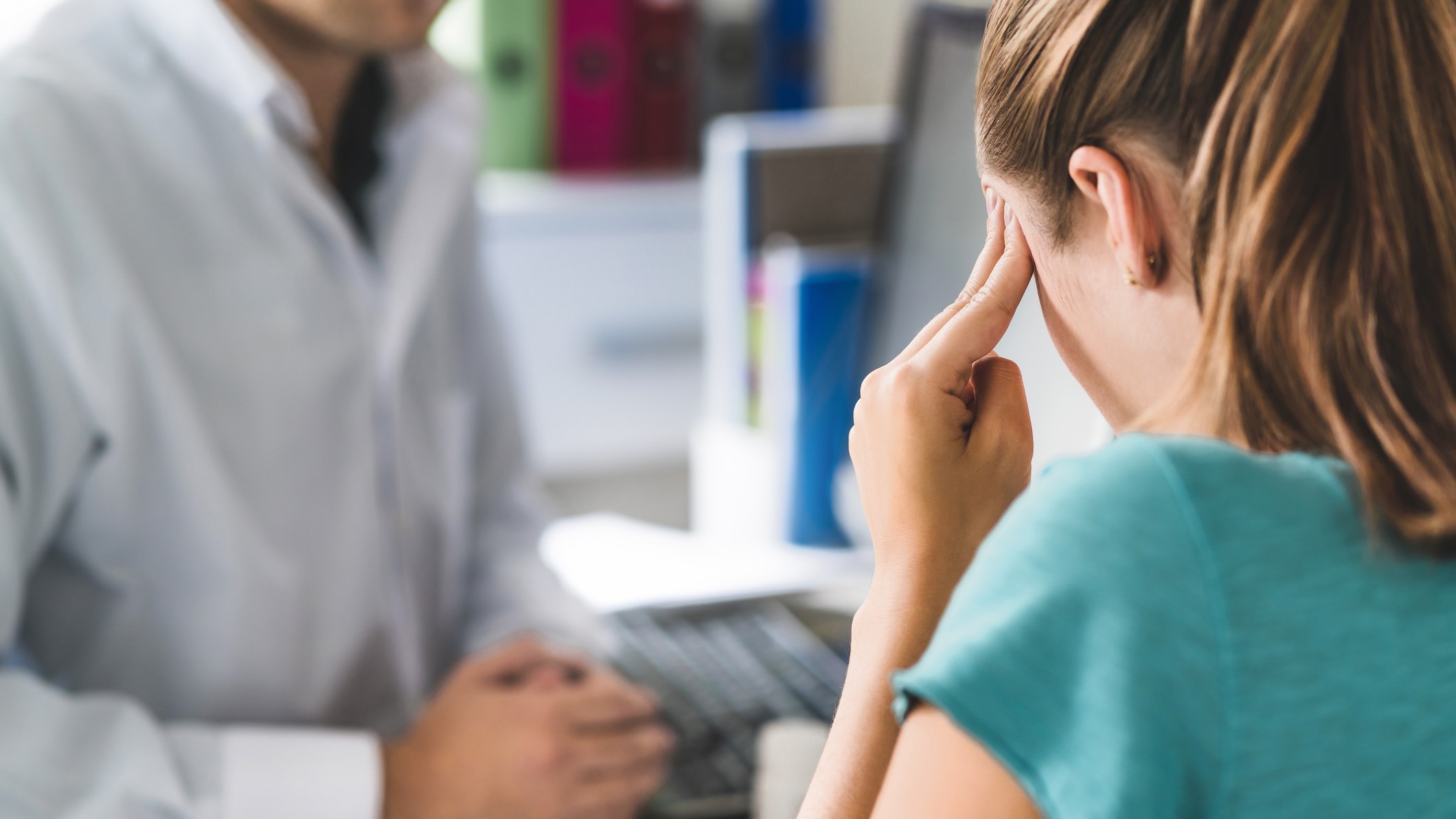A woman with a headache talking to her healthcare provider.
