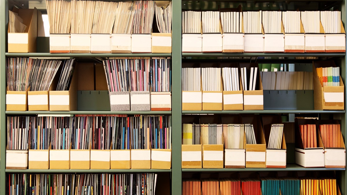 Four shelves of books and reports in a library.