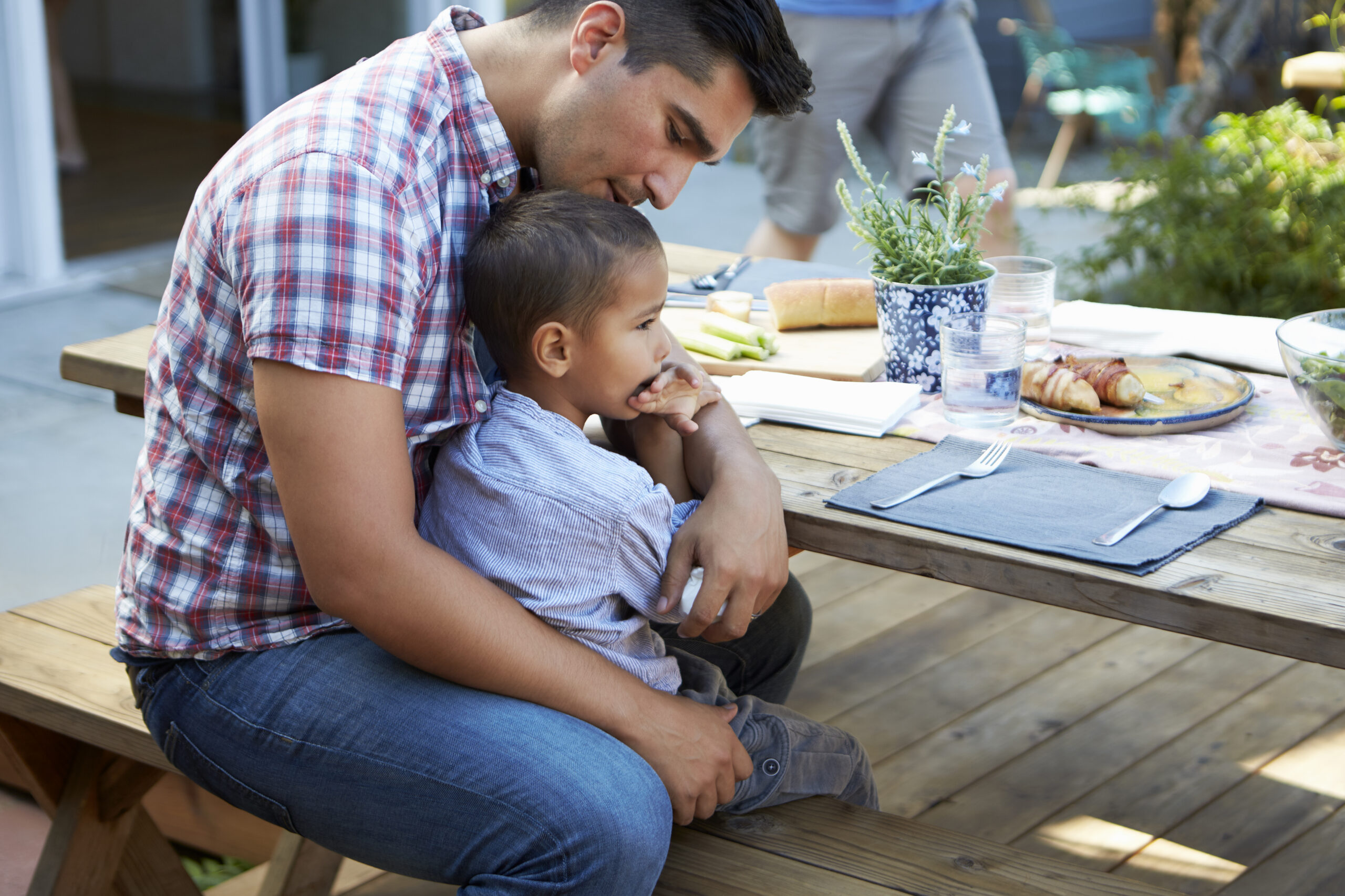 Dad sitting with young son at a picnic table