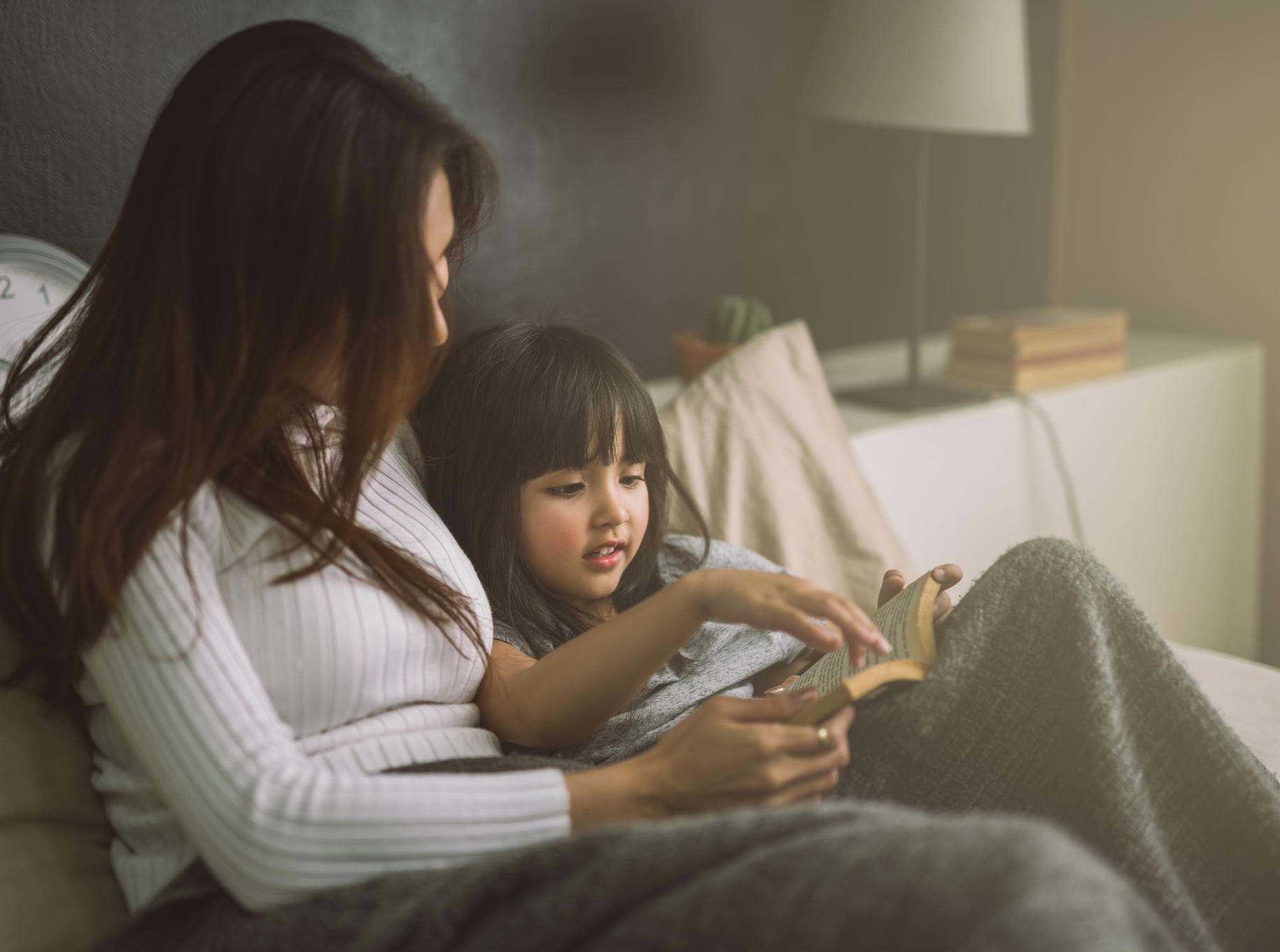 Mom and toddler daughter reading a book together