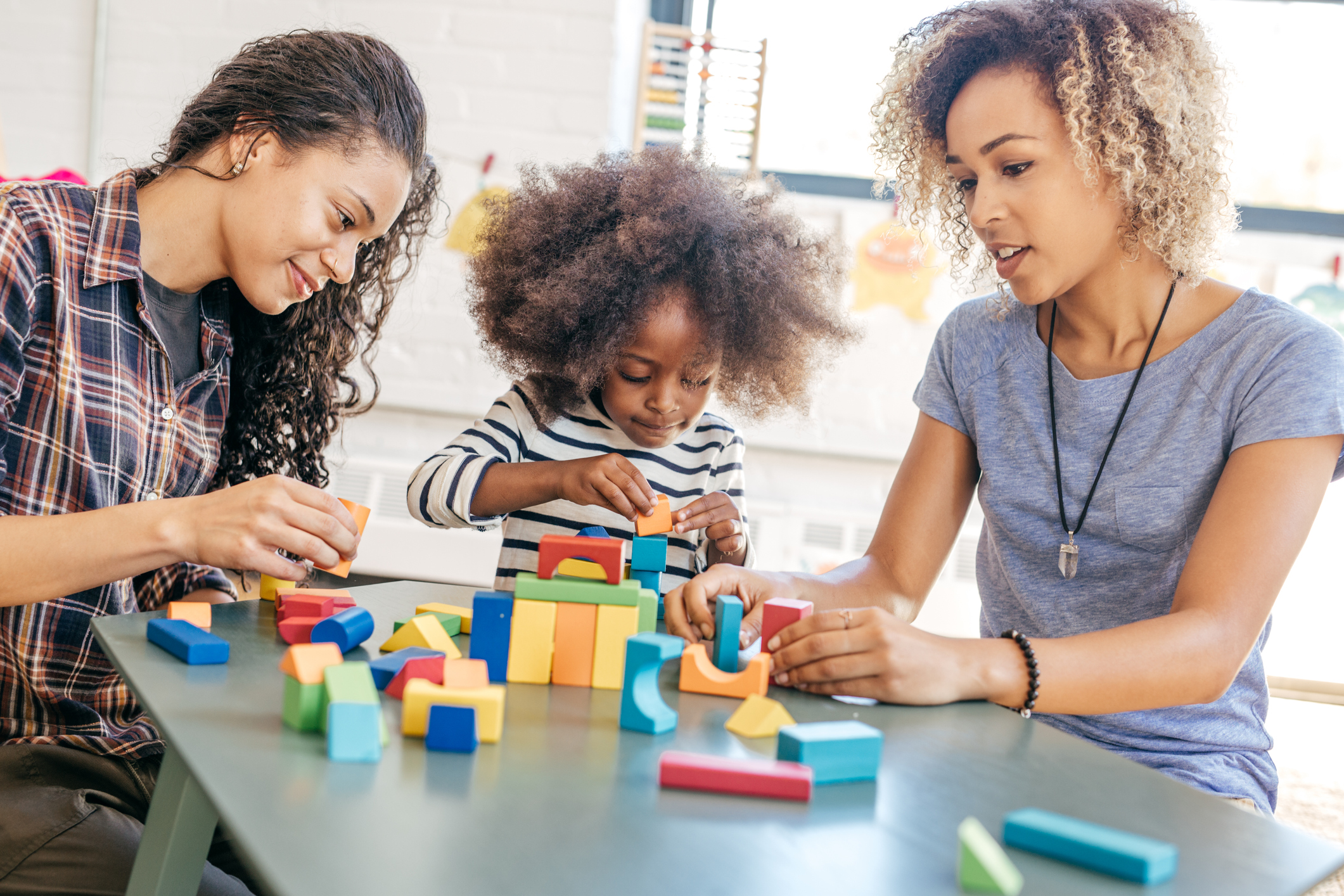 Two women playing with blocks with preschool girl