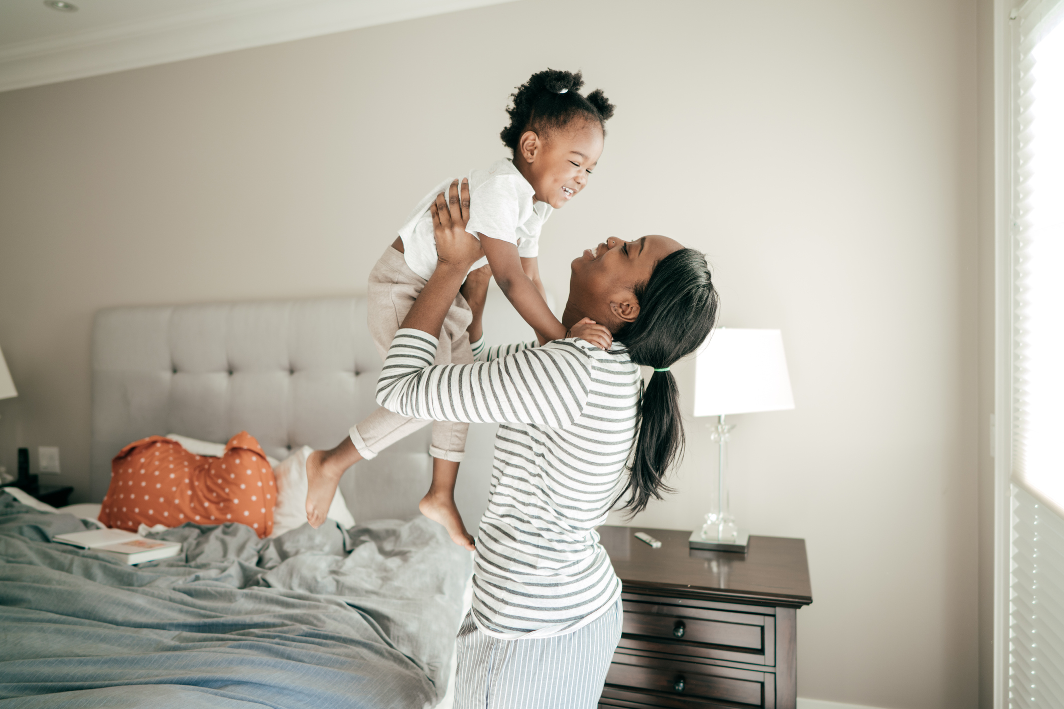 Mom lifting up laughing toddler girl