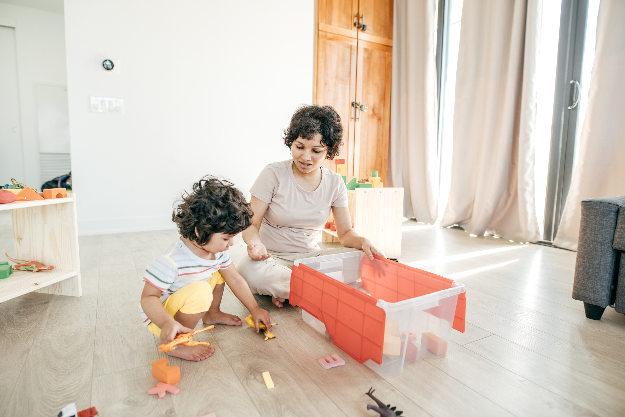 Mom helping toddler pick up toys