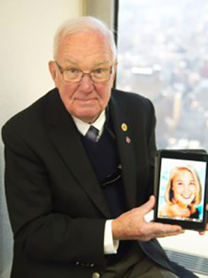 Carl J. Flatley seated by a window holding a picture of his daughter.
