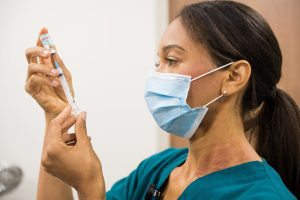 Healthcare worker drawing up vaccine dose from a multi-dose vial