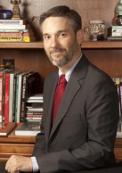 A photograph of Dr Samuel F. Posner appears behind a desk in front of a bookshelf.
