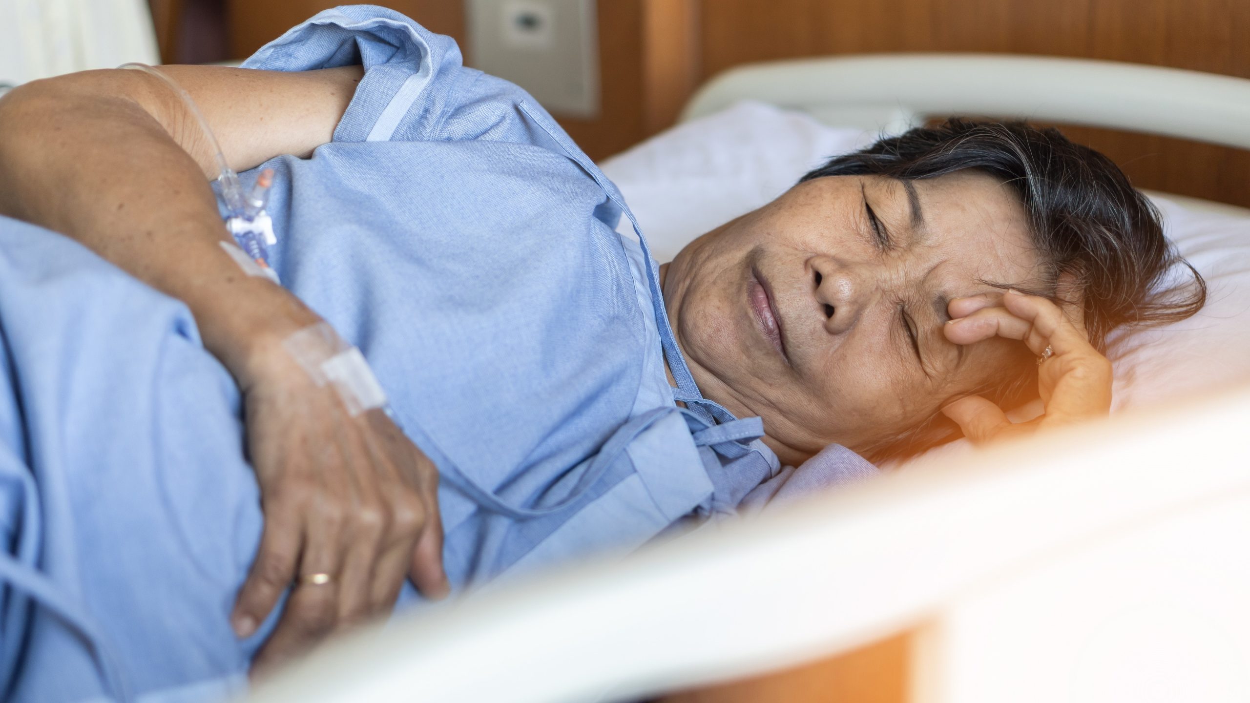 A woman who is sick lies in a hospital bed.