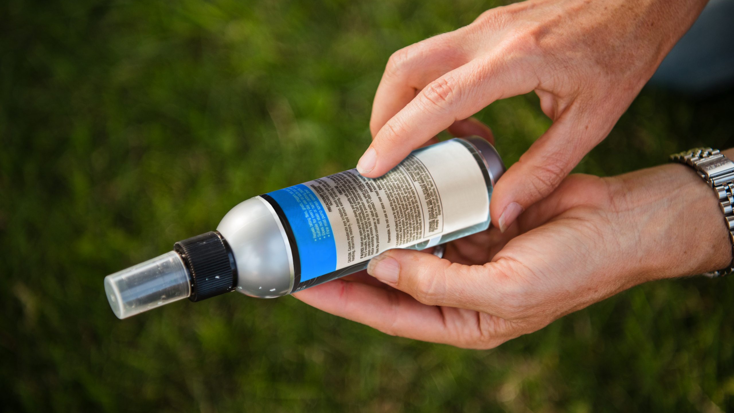 A person reads the ingredients on the back of a bottle of insect repellent.