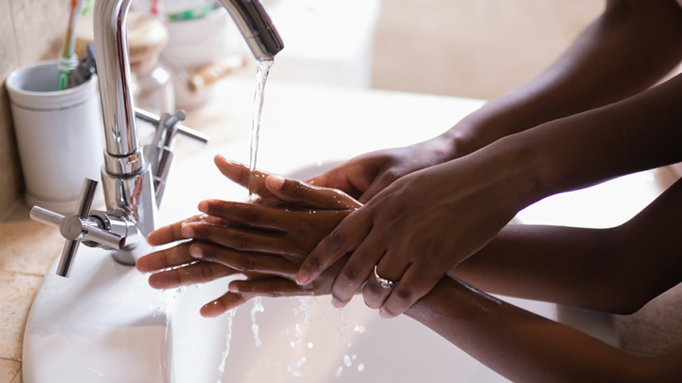 lead by example Close-up of black hands under a tap, a mother showing her child how to wash hands properly.