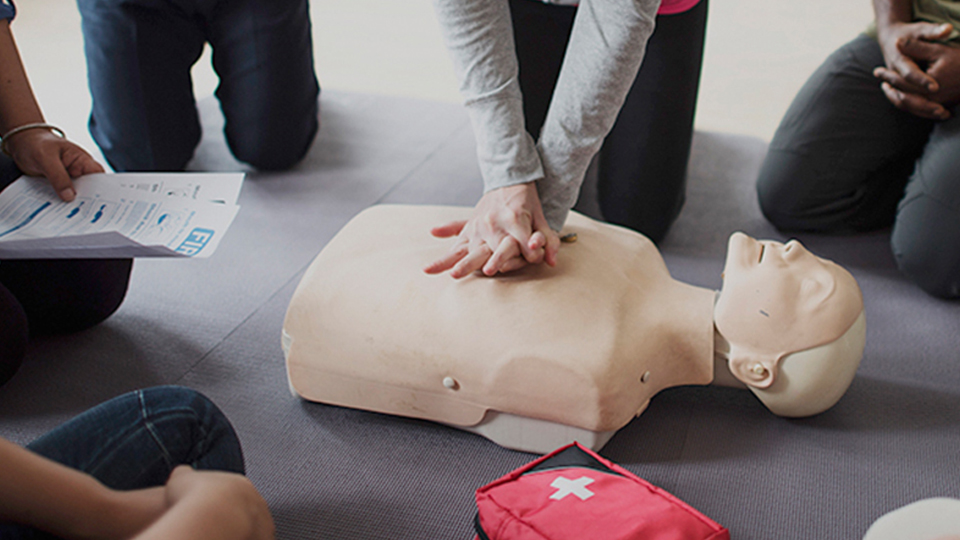 practical skills Group of people in a circle learning resuscitation with a mouth to mouth practice mannequin.