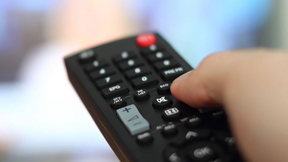 stay informed Close-up of a hand holding a tv remote.