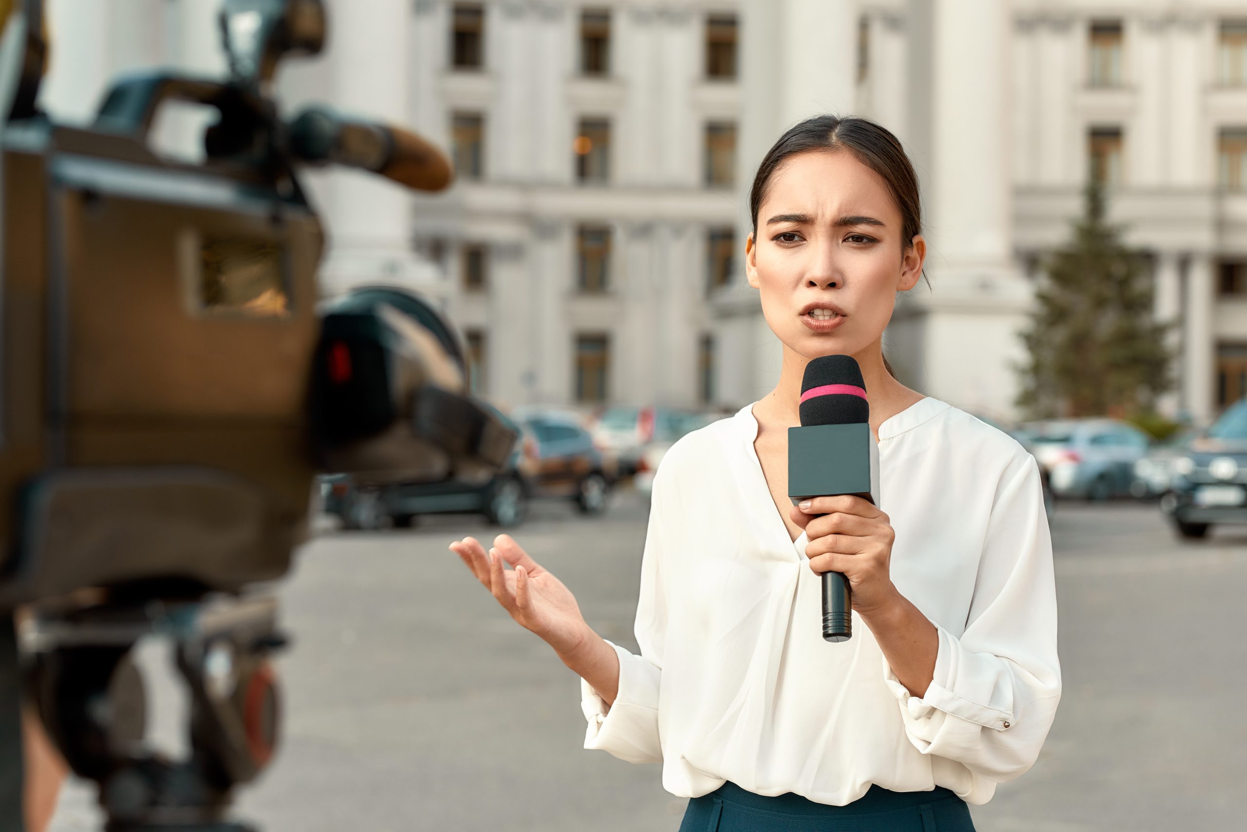 Reporter Live Streaming image 271 KB A female reporter is speaking into a camera while holding a microphone during a live steam on a street