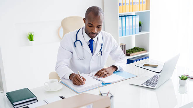 Clinician checking reference documents A clinician sitting at a desk referring to some reference documents.