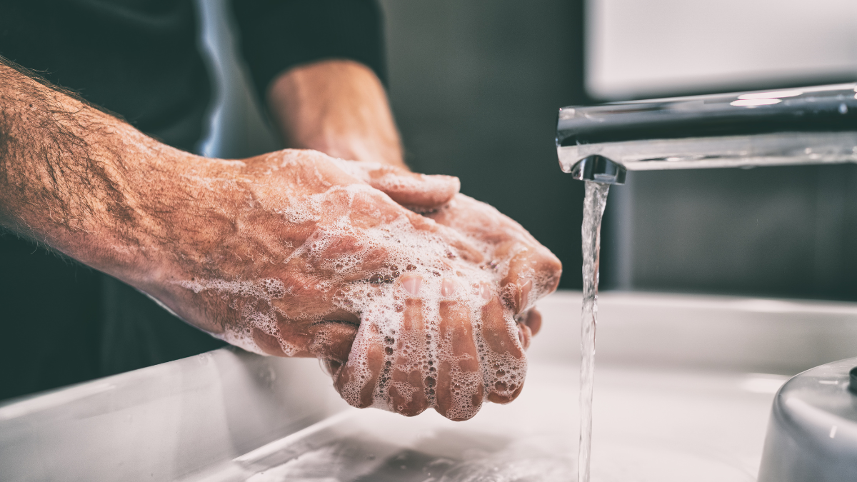 Man soaping up his hands over a bathroom sink.