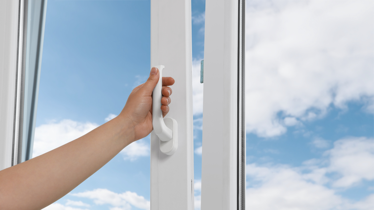 A hand opening a window on a beautiful day.