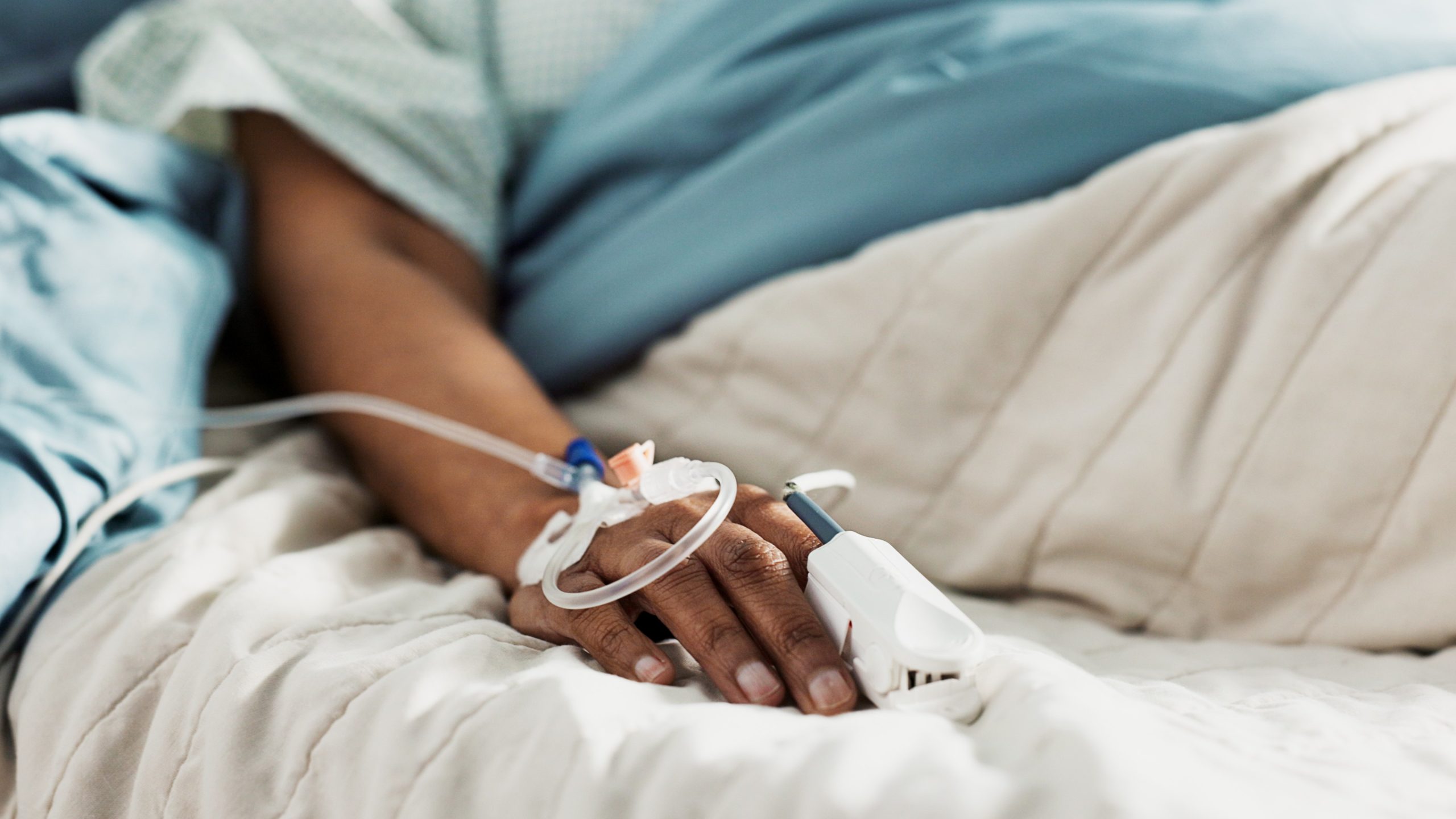 Patient in a hospital bed with an intravenous drip line.
