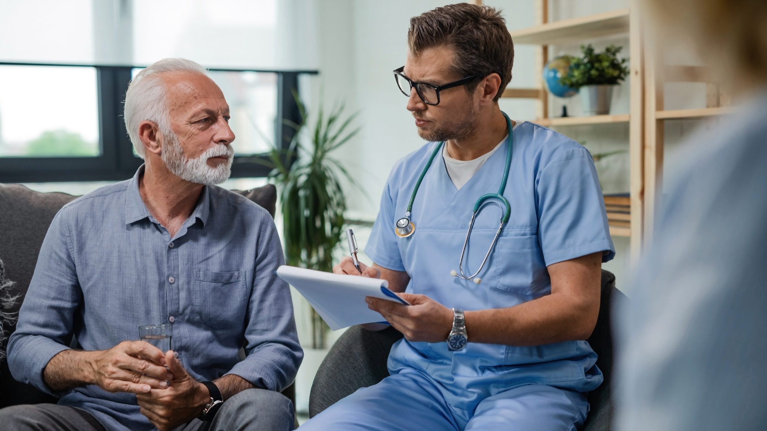 Doctor taking notes with older male patient