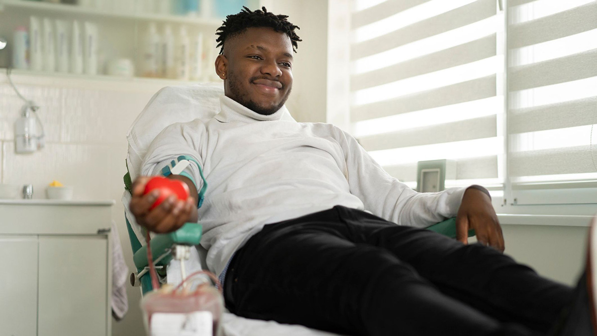 A man who is donating blood A man who is smiling while donating blood