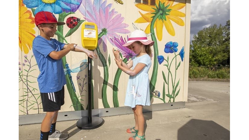 Kyle and Hayley Davis apply sunscreen from a dispenser at a City of Reno park