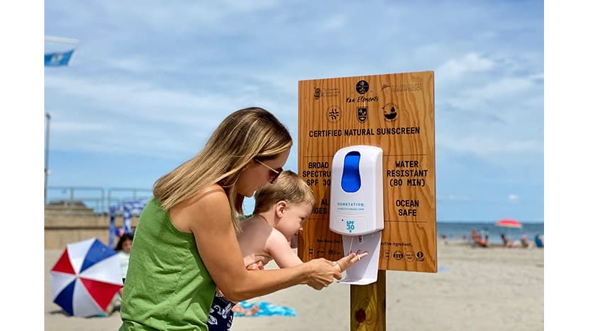 Terri helps her son Kai apply sunscreen from a dispenser at Scarborough State Beach in Narragansett, Rhode Island.