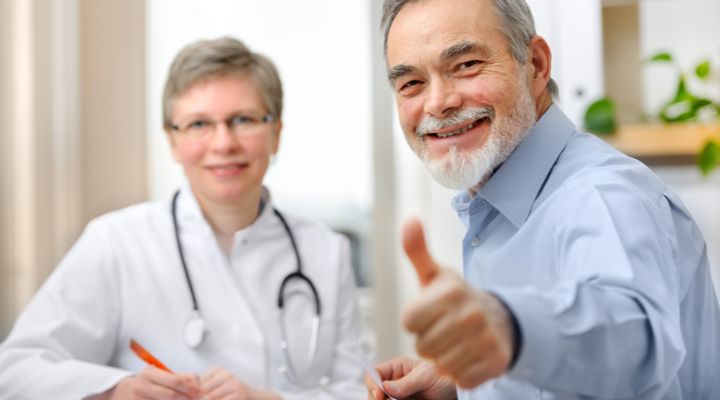 Un paciente junto con su m&eacute;dico, sonriendo con su pulgar arriba