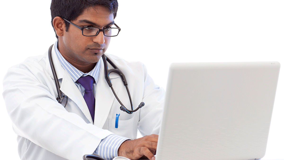 Male healthcare provider with serious face working on laptop