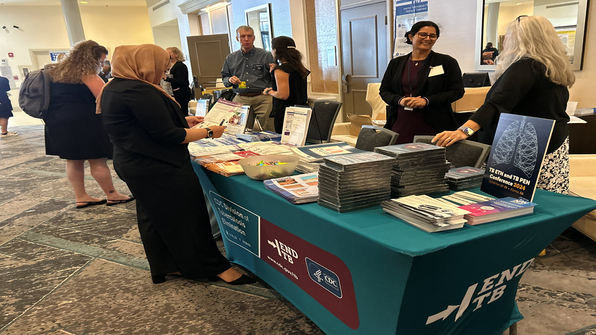Booth TB ETN and PEN Conference 2024 People interacting at a CDC booth with educational materials on TB elimination at a health conference.