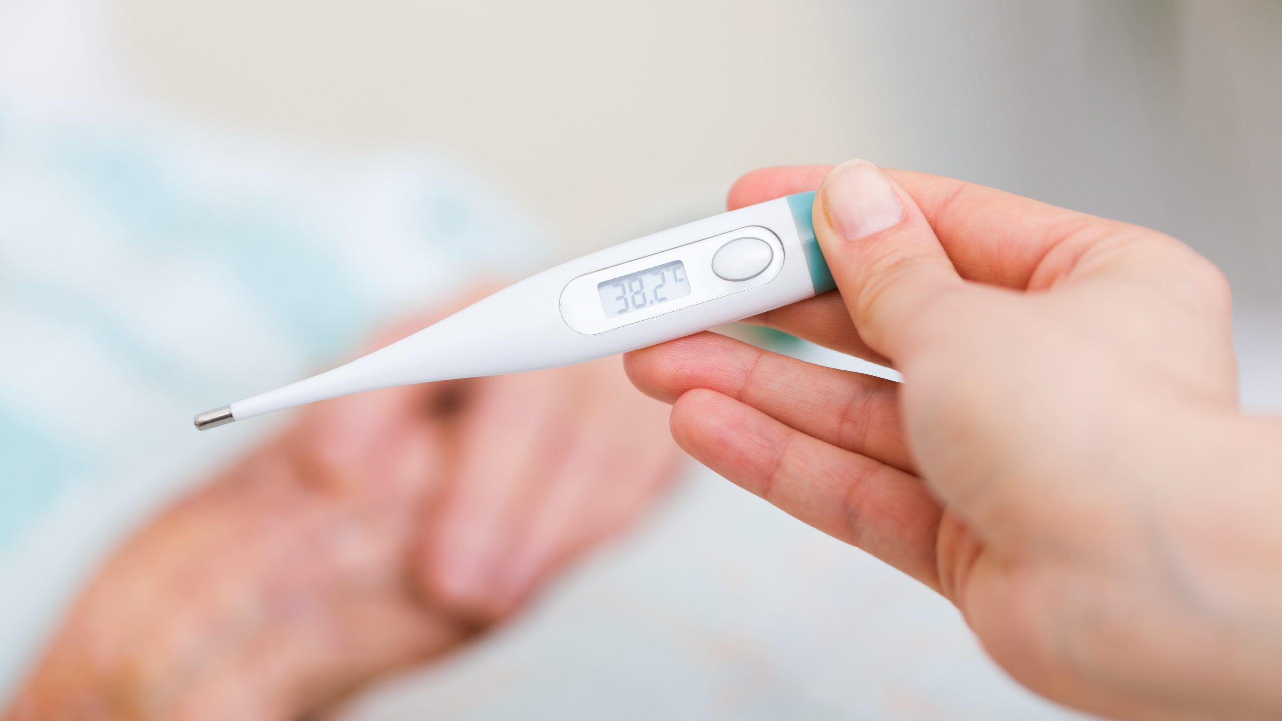 A person holds a Celsius thermometer in their hand.