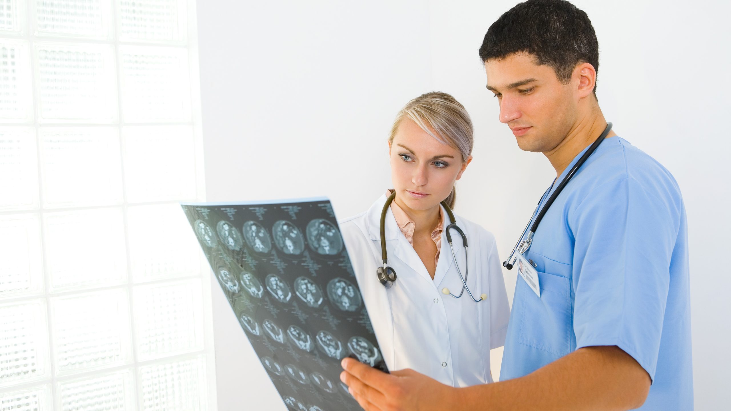 A female doctor and male healthcare specialist look at the results of a brain scan.