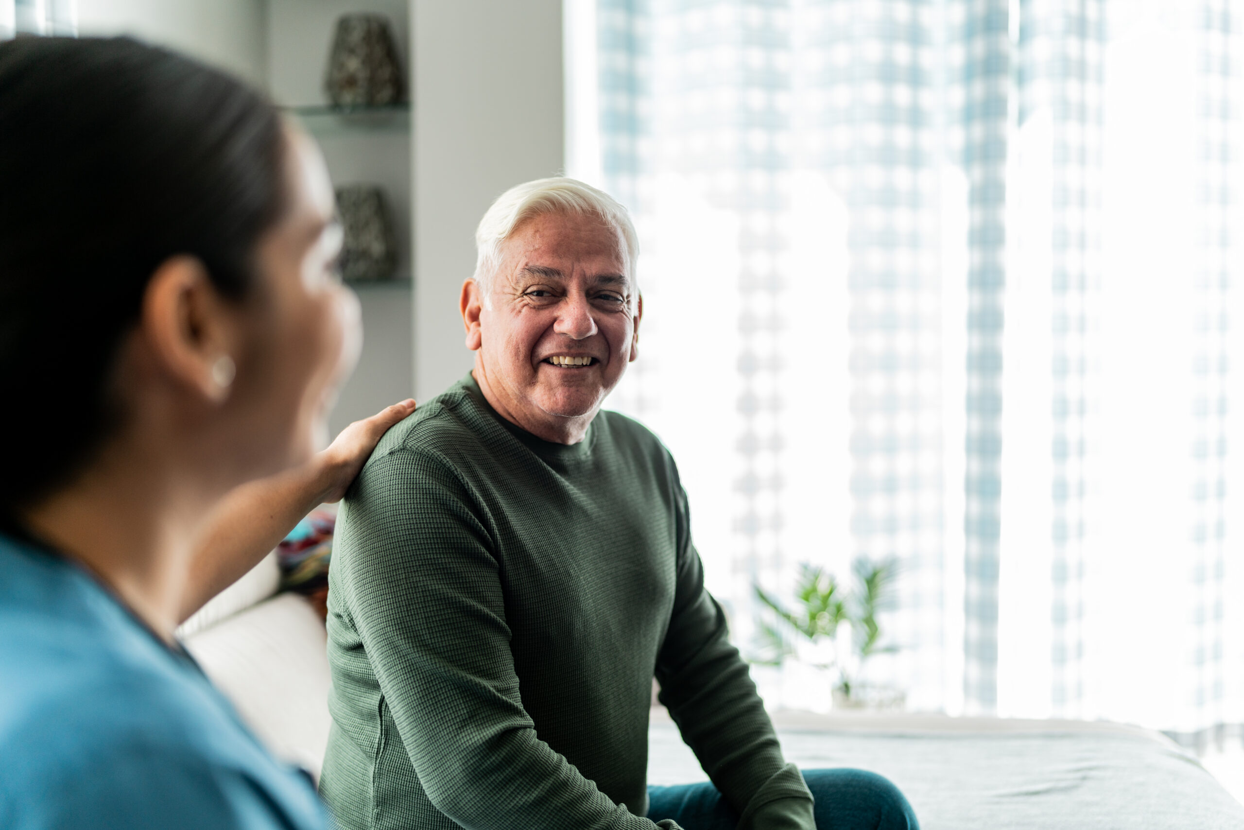 Healthy older man smiling and talking with a healthcare provider