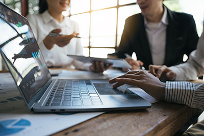 Team of business investment consultant analyzing company annual financial report working with documents pie and donut chart, using laptop
