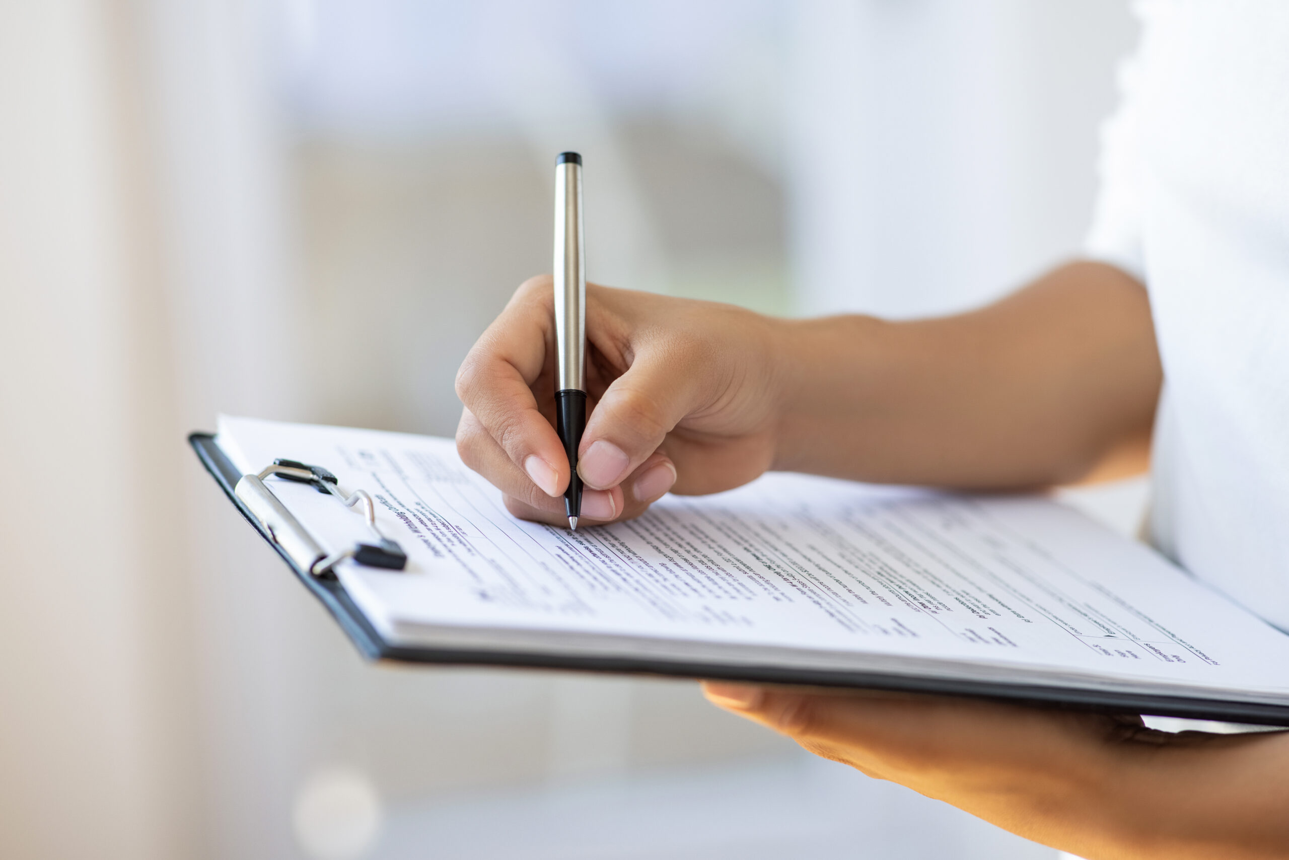 A person writes on a clipboard