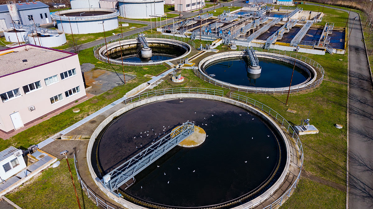 Aerial view of a wastewater treatment plant with circular tanks and processing basins.
