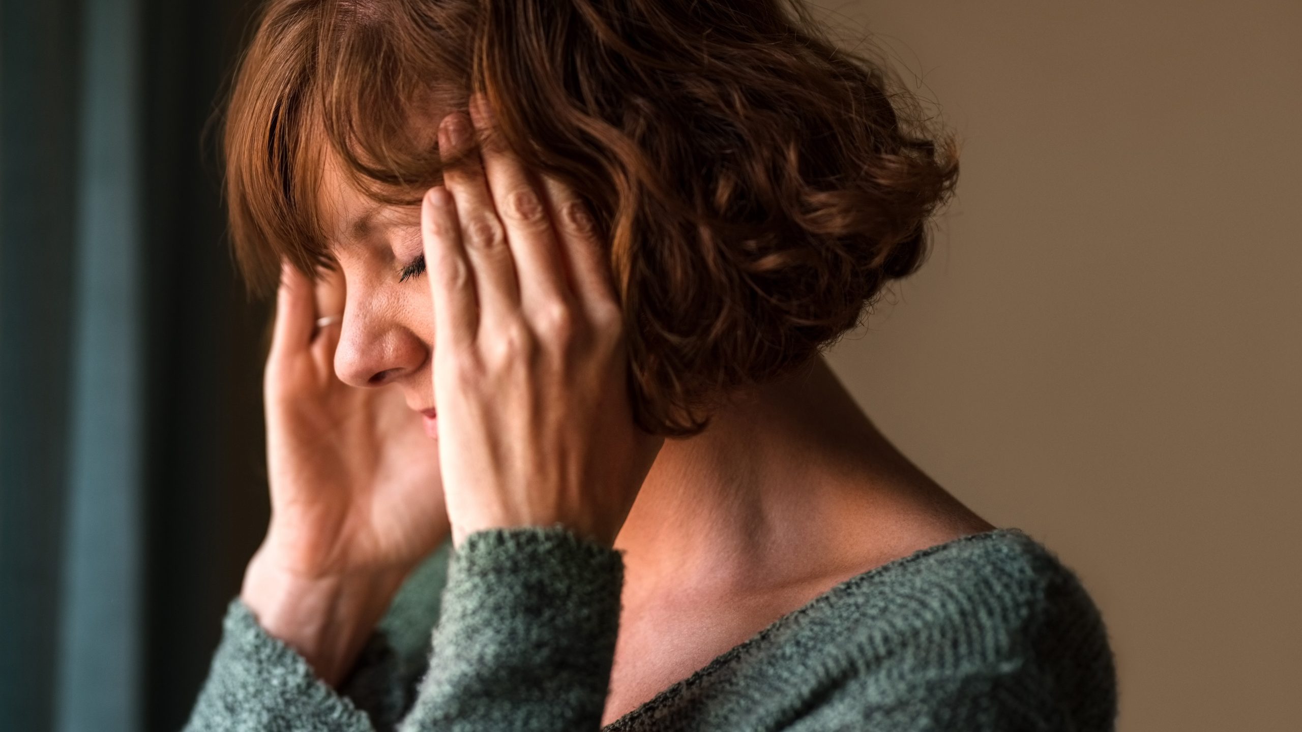 Woman holds her head in pain.