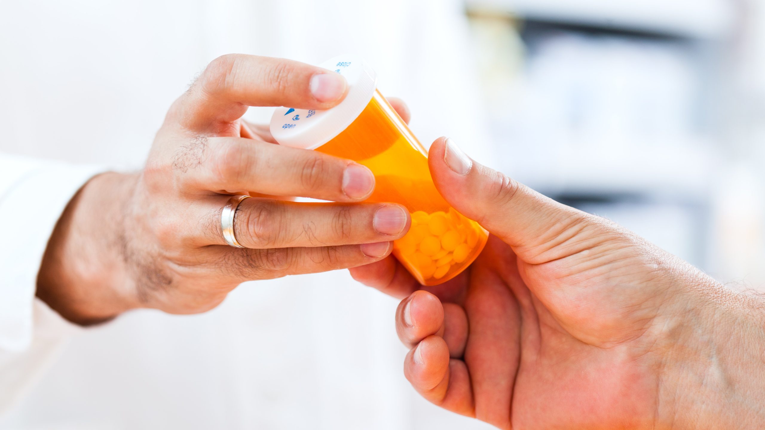 Doctor handing a bottle of medication to a patient.