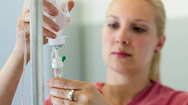 Female nurse setting up an IV drip for a patient.