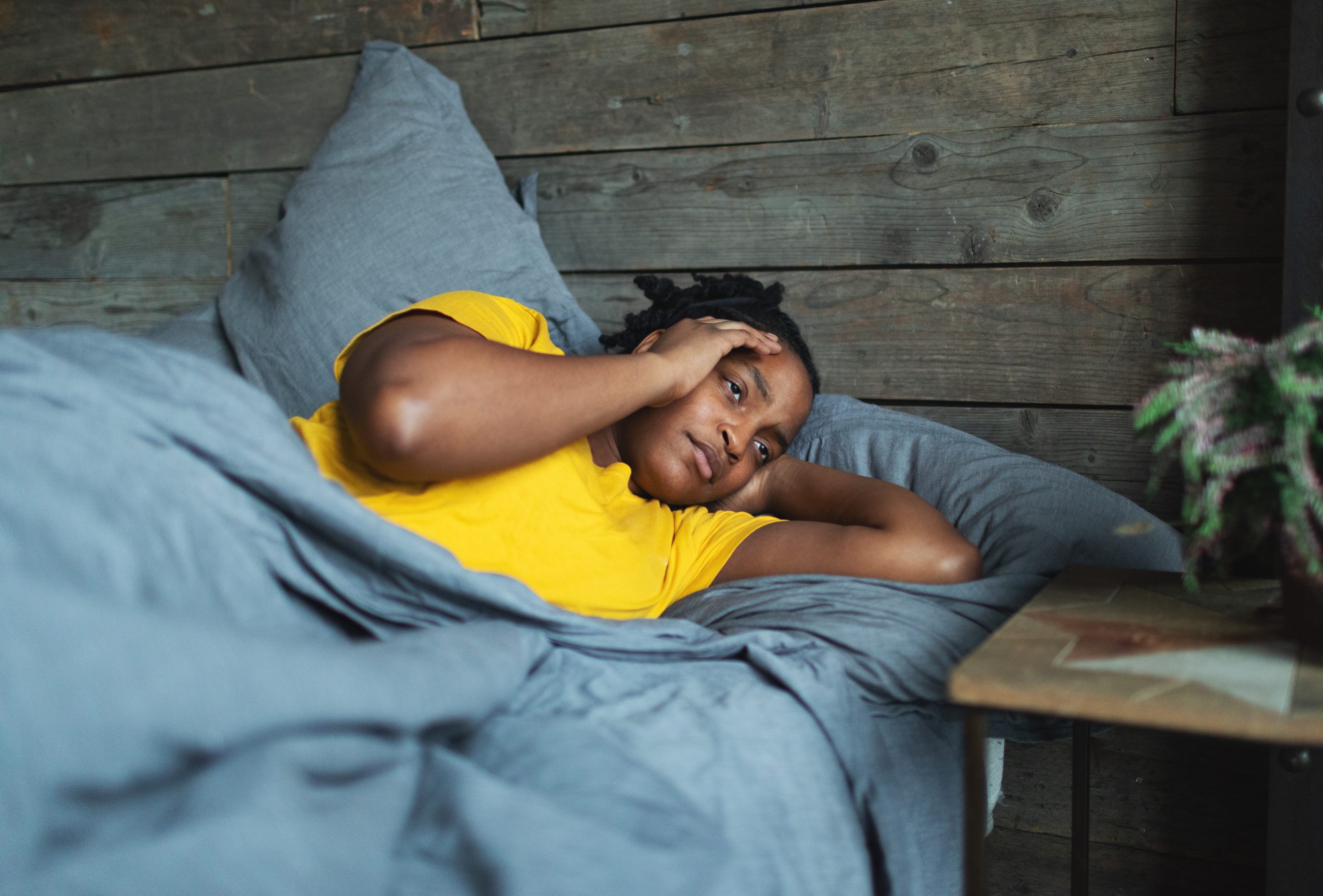 Traveler lying in bed with a hand on their head.
