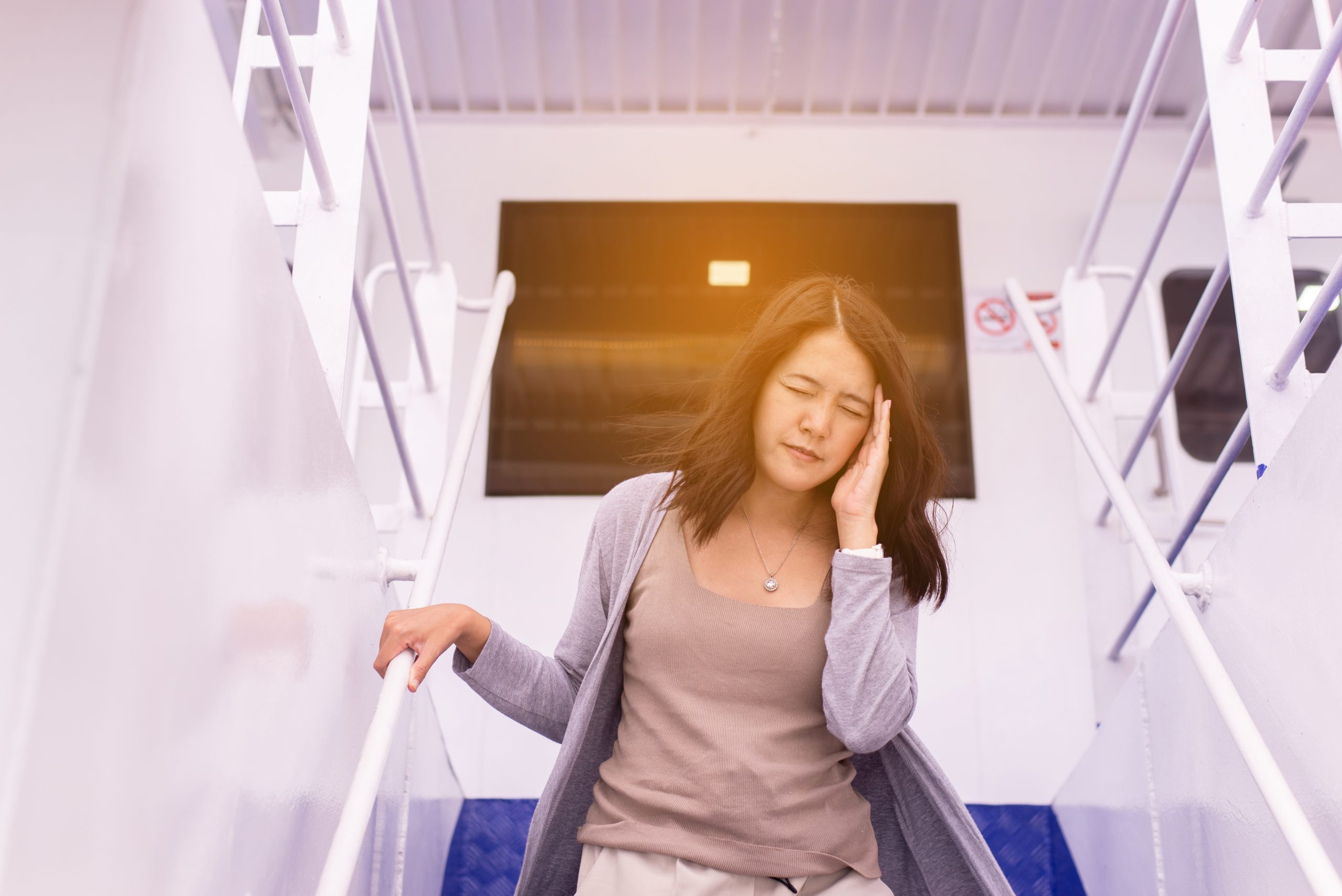 Traveler suffering from motion sickness on a boat holds onto a rail.