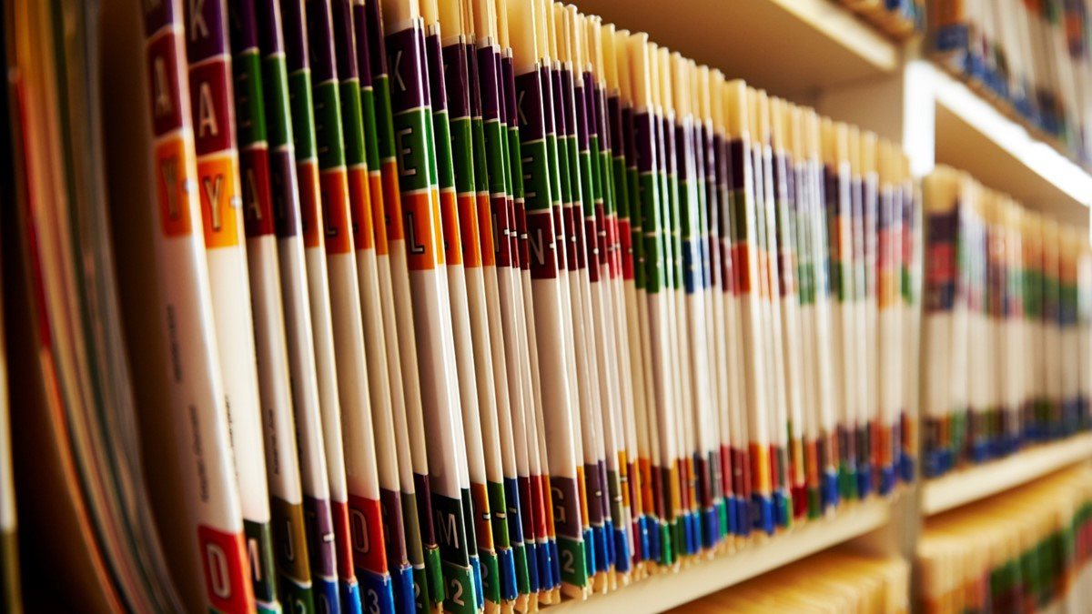 Three shelves are filled with bound medical reports.